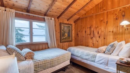 two beds in a room with wooden walls at Maxwelton Aerie Bluffside Retreat w Sweeping Puget Sound Views Firepit in Clinton