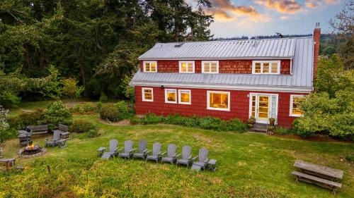 a red house with a group of chairs in the yard at Maxwelton Aerie Bluffside Retreat w Sweeping Puget Sound Views Firepit in Clinton