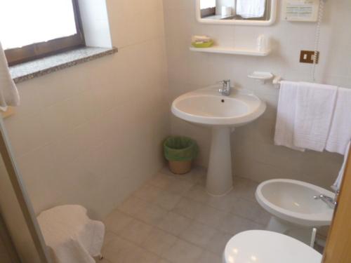a white bathroom with a sink and a toilet at Albergo Negritella in Borgo