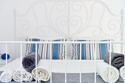 Una cuna blanca con mantas y almohadas encima. en AMMOR Beach houses, Nisida, en Áno Fanárion