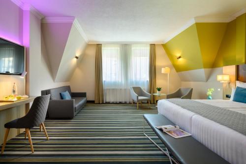 a hotel room with a bed and a couch at Leonardo Hotel Budapest in Budapest