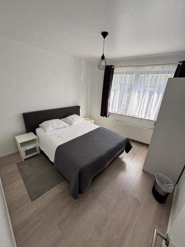 a white bedroom with a bed and a window at Stylish, modern & spacious apartment in Brussels in Brussels