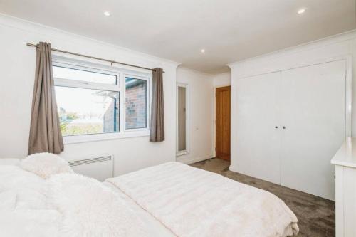 ein weißes Schlafzimmer mit einem Bett und einem Fenster in der Unterkunft Modern coastal 1 bed flat in Shoreham in Lancing
