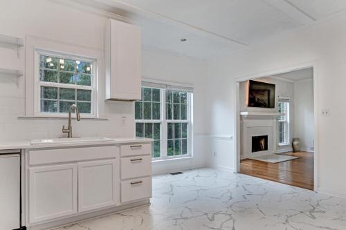a white kitchen with a sink and a fireplace at Modern 1- Queen Bed On Quiet Block in Hephzibah