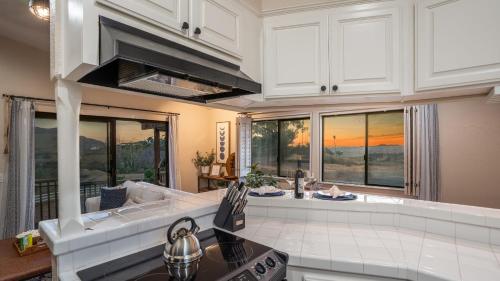 RainbowにあるScenic Deck w Sunset Views Near Temecula Wineries Estrada Ranch by AvantStayの白いキャビネットと大きな窓のあるキッチン