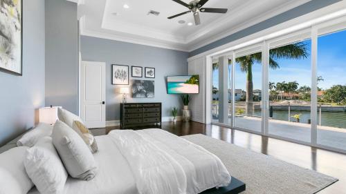 a bedroom with a white bed and a large window at Marco Polo by AvantStay Waterfront 5BDR Pool Spa Fire Pit Walk to Beach in Marco Island