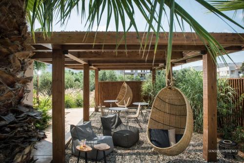 eine Terrasse mit Stühlen und Schaukeln unter einer Pergola in der Unterkunft Sensus Experience by Lavris in Gouves