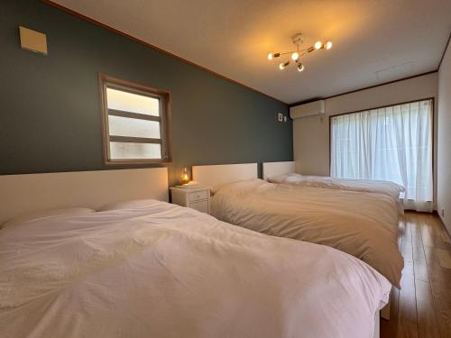 2 camas en un dormitorio con ventana en UMI&kanzanji, en Hamamatsu