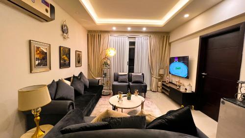 a living room with black couches and a tv at Gold Crest Luxury Serviced Apartments City View DHA Lahore in Lahore