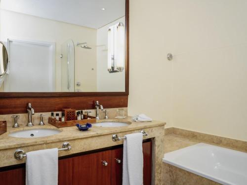 a bathroom with two sinks and a large mirror at Le Médina Essaouira Thalassa Sea & Spa - MGallery Collection in Essaouira