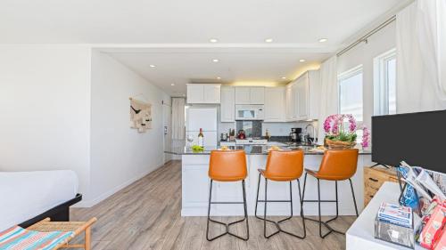 a kitchen with orange bar stools in a living room at 2 Coastal Studios at Cayucus Beach Access Ocean Views in Cayucos