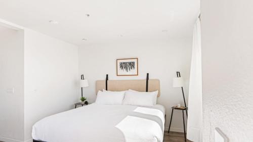 a white bedroom with a white bed and two lamps at 2 Coastal Studios at Cayucus Beach Access Ocean Views in Cayucos