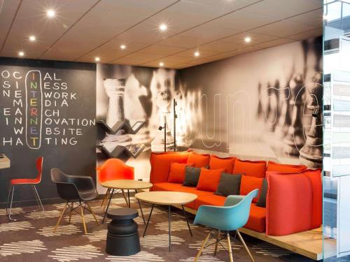 a lobby with an orange couch and tables and chairs at Ibis Poznan Stare Miasto in Poznań