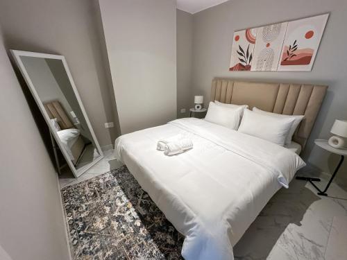 a bedroom with a large white bed and a mirror at 2BR Duplex in Masdar 5 Mins to Abu Dhabi Airport in Abu Dhabi