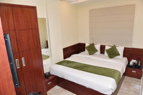 a small bedroom with a bed with white sheets and green pillows at Mertiya Residency in Jodhpur