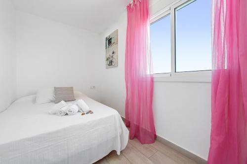 a bedroom with a bed with pink curtains and a window at PINEDA III Apartment in La Pineda