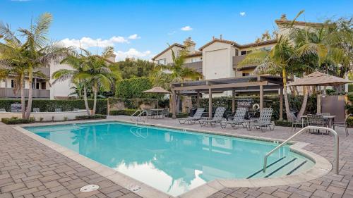 a swimming pool with chairs and a building at Coastal Retreat w Pool Spa BBQ Near Beaches Golf Courses Ritz Pointe Condo by AvantStay in Dana Point