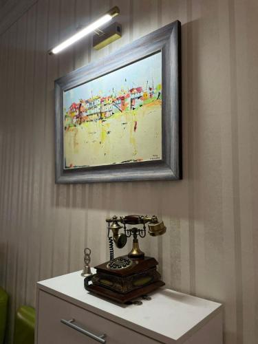 a painting of a beach and a phone on a cabinet at Happy Rustavi guest house in Rustavi