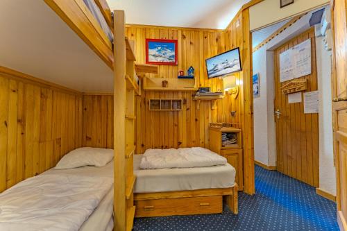 Dos camas en una habitación con paredes de madera. en Enjoy Charming Machu, en Val Thorens