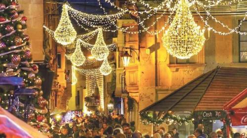 a crowd of people standing in a street with christmas lights at Maleth Inn in Rabat