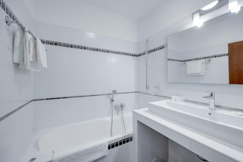a white bathroom with a tub and a sink at Hotel ANTARES in Bratislava
