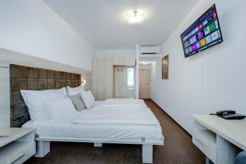 a bedroom with two beds and a tv on the wall at Hotel ANTARES in Bratislava