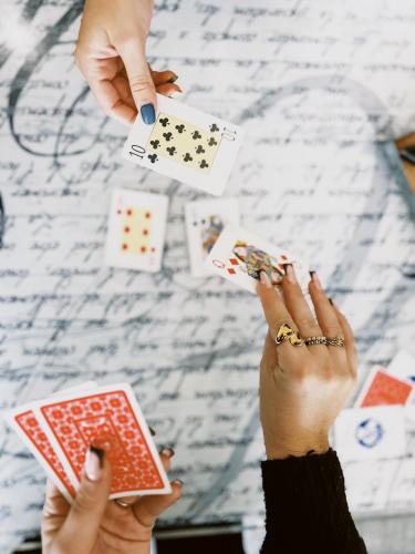 two hands holding playing cards and a pile of playing cards at The Originals Boutique, Hôtel Neptune, Montpellier Sud in Carnon-Plage