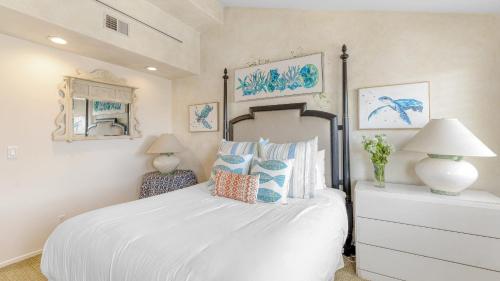 a bedroom with a large white bed with blue pillows at Shoreline Villa by AvantStay Steps to the Beach Bay Pier in Newport Beach