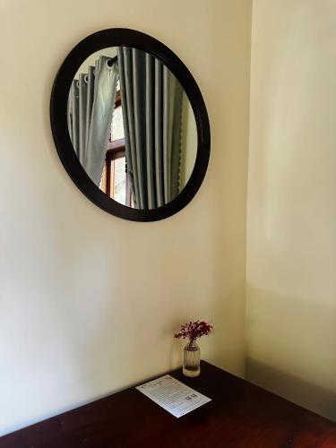 a mirror on a wall with a vase on a table at Chez Vous House - Toom Sara in Mang Son