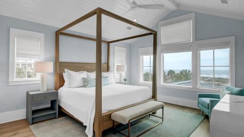 une chambre avec un lit à baldaquin avec une chaise et des fenêtres dans l'établissement 3108 Palm by AvantStay Oceanfront Private Pool Incredible Views, à Isle of Palms