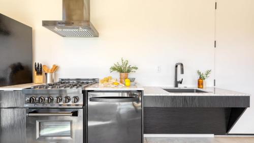 a kitchen with a stainless steel stove and a sink at Blackhaus Full Buyout by AvantStay 16-Room Hotel in Palm Springs