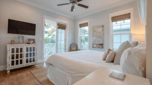 a white bedroom with a bed and a flat screen tv at No Shady Beaches by AvantStay Seacrest Beach Pool Bikes in Rosemary Beach