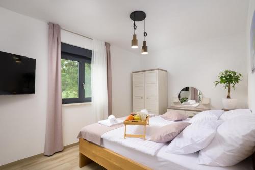 a white bedroom with a large bed with a chair on it at Villa Japlenica by Istrialux in Žagrići