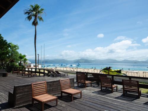 a boardwalk with chairs and a beach with a palm tree at i + Land Nagasaki in Nagasaki