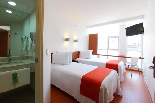 a hotel room with two beds and a television at One Ciudad de Mexico Alameda in Mexico City