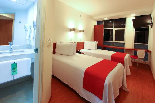 a hotel room with two beds and a bathroom at One Ciudad de Mexico Alameda in Mexico City