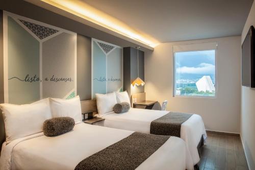 a hotel room with two beds and a window at One Ciudad de Mexico Alameda in Mexico City
