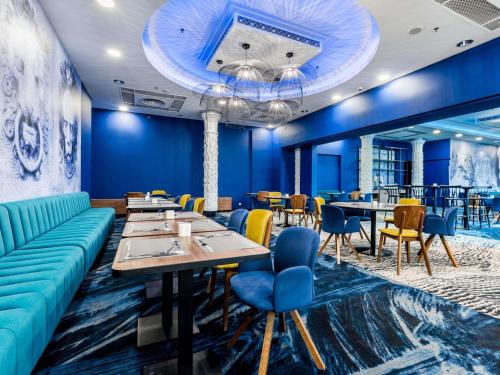 a restaurant with blue walls and tables and chairs at Mercure Gdańsk Stare Miasto in Gdańsk
