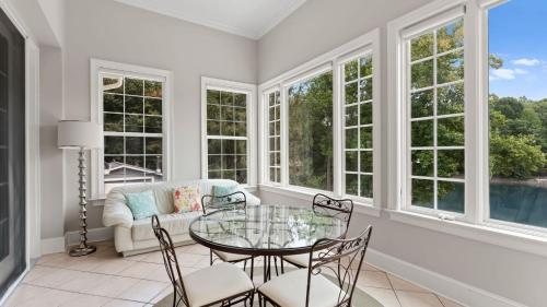 a living room with a glass table and chairs and windows at Whitetail Cove by AvantStay Lakefront w Pool Private Dock Sleeps 20 in Terrell