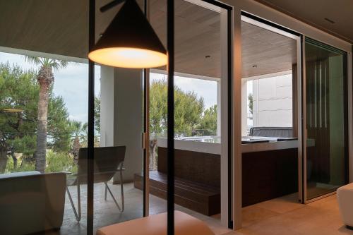 a living room with glass walls and a table and a lamp at Hotel Relax Family & Spa in San Benedetto del Tronto
