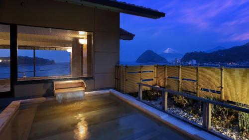 a balcony with a view of the ocean at night at Izu Mitohama Shotokan in Numazu