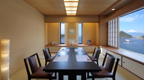 a dining room with a table and chairs and a large window at Izu Mitohama Shotokan in Numazu