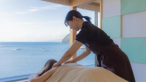 a woman is waxing a woman on a bed at Izu Mitohama Shotokan in Numazu