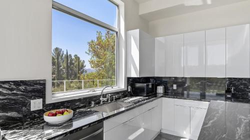a white kitchen with a sink and a window at Luxe LA Escape w Pool Views Game Room Alta Vista Estate by AvantStay in Los Angeles