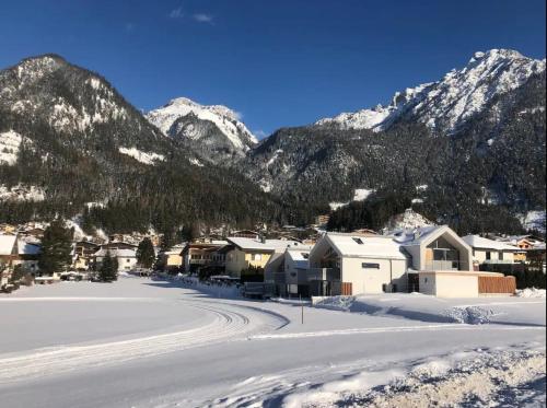 a snow covered village with mountains in the background at TIROLER TRIS modern villa 10 beds in Maurach