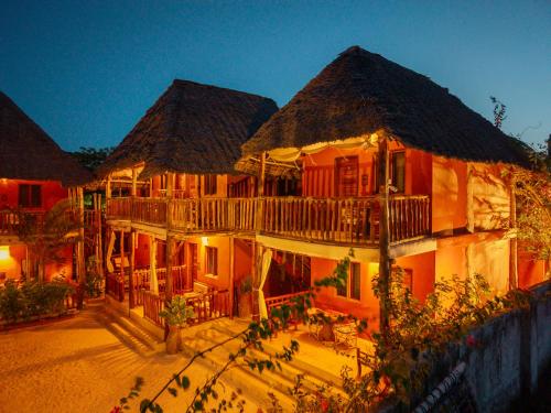 a large building with a porch and balcony at night at Shanuo Beach Bungalows in Michamvi