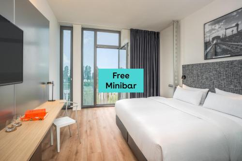 a bedroom with a bed and a desk and a window at INNSiDE by Meliá Bremen in Bremen