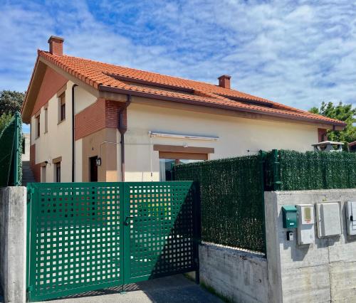 ein Haus mit einem grünen Tor davor in der Unterkunft Casa Vacacional el Mirador de Picos in Serdió