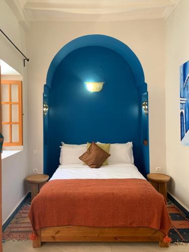 a bed with a blue headboard in a bedroom at Riad Mazal Mogador in Essaouira