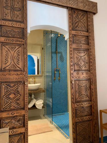 a bathroom with a shower with a glass door at Riad Mazal Mogador in Essaouira